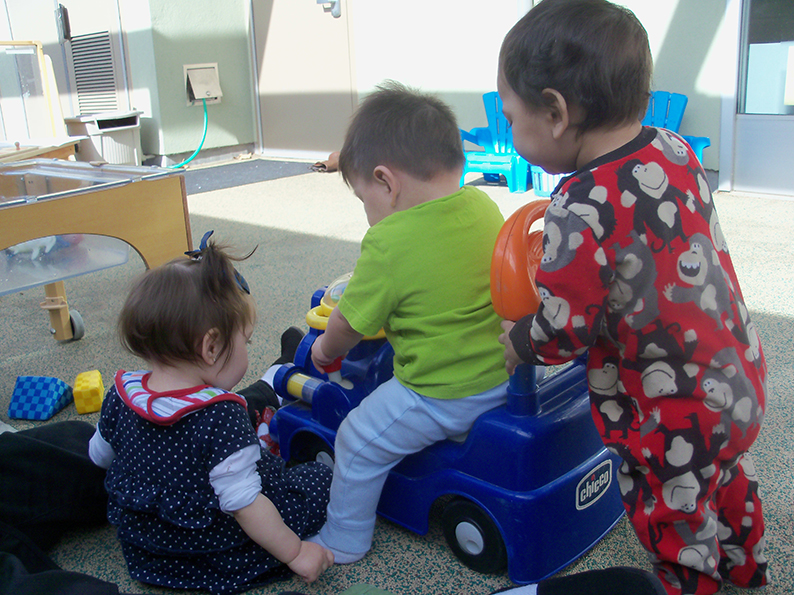 three children playing with toy car